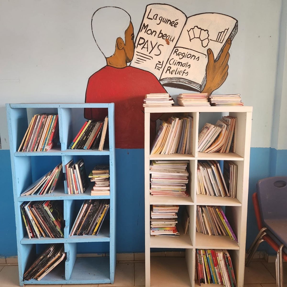 Espace bibliothèque avec livres et fresque murale.